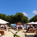 Panoramic view of Pao Pao Beach Club with sun loungers on the sand and blue ocean background.