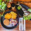 Dinner setting with grilled fish, rice, and vegetables on a wooden table.